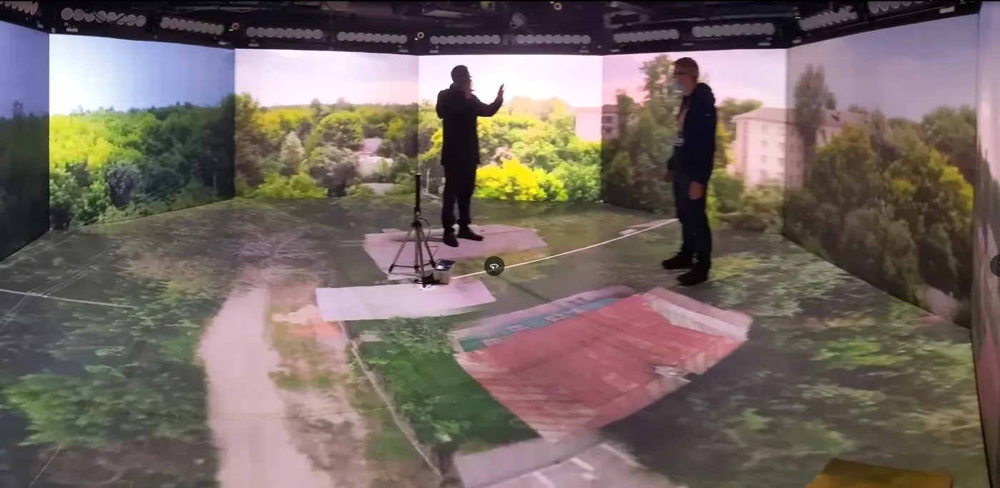 Two people standing in a photogrammetry-reconstructed landscape projected across walls and floor